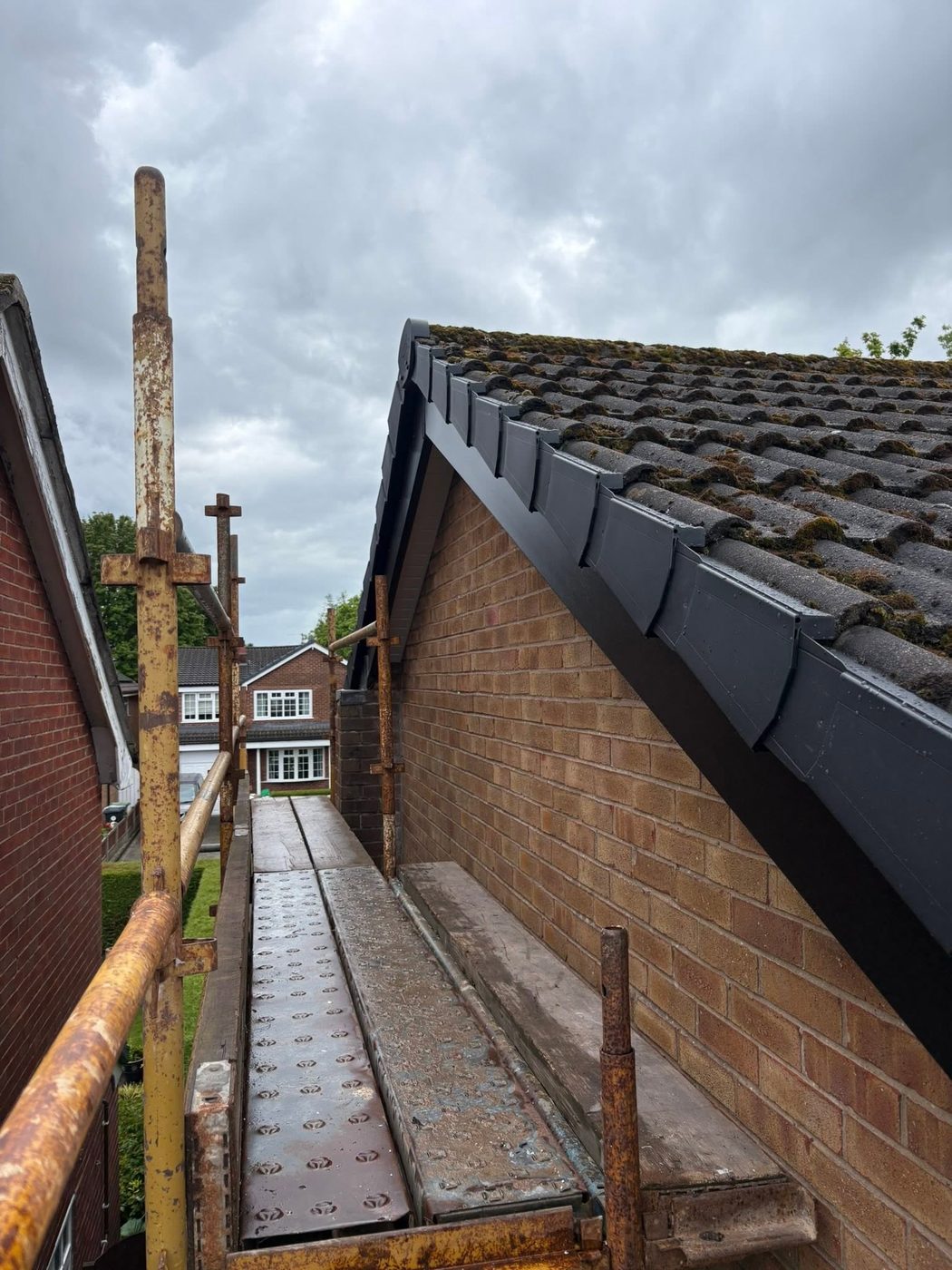 New anthracite grey uPVC fascia, bargeboard and dry verge fitted to a gable end, photographed from the scaffold platform