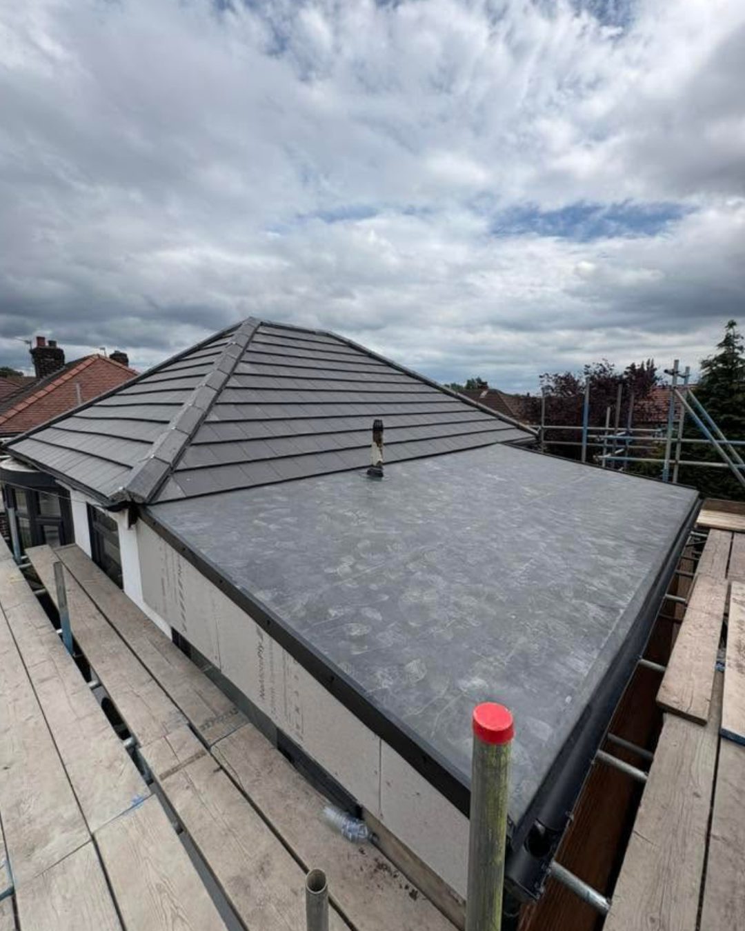 The completed re-roof with new dark grey slate tiles and a new rubber EPDM flat roof section