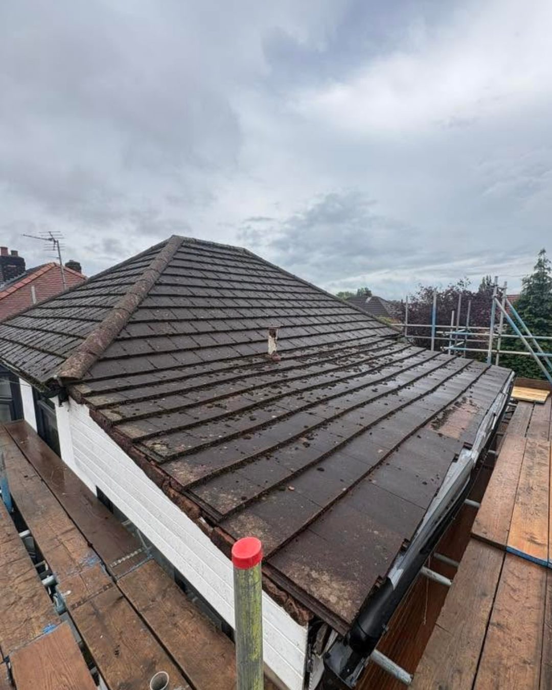 The worn original roof before stripping, with mossy brown concrete tiles and an old felt flat roof section