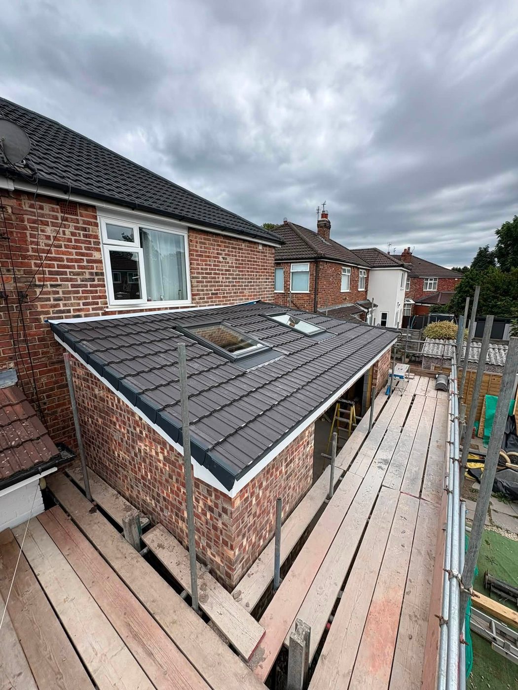 Two finished Velux roof windows fitted into a newly tiled grey extension roof, with neat flashings and white trims to the verges